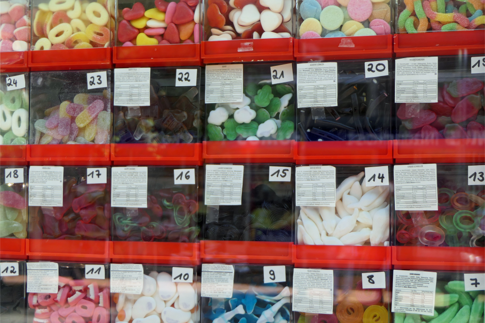 Zu sehen sind verschiedenste Süßigkeiten in kleinen, durchsichtigen Plastikschubladen.